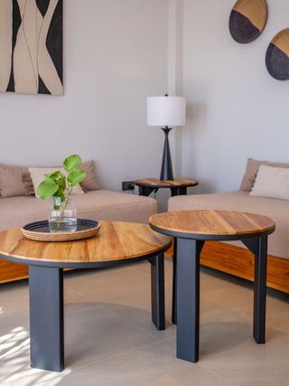 The photo shows an elegant living room designed in a modern, minimalist style. Wooden tables, light-colored sofas, and decorative accents create a warm and stylish space for relaxation.